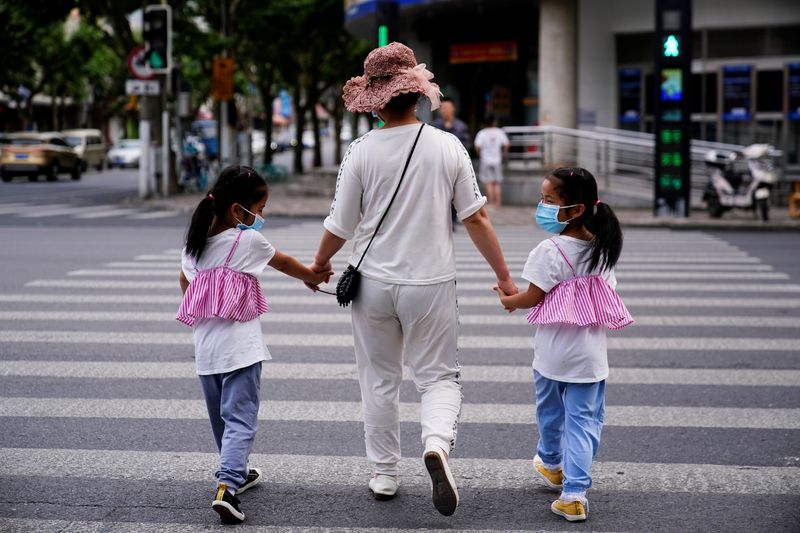 file photo: a mother walks with her twin daughters on a street in shanghai